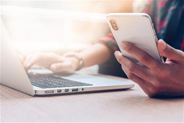 person with phone and laptop shutterstock_1232899081