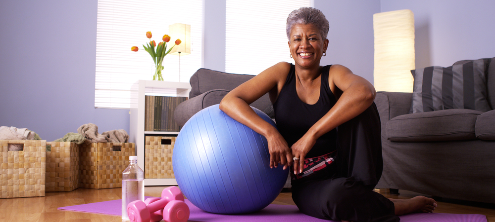 Older woman sitting on floor with yoga ball and weights